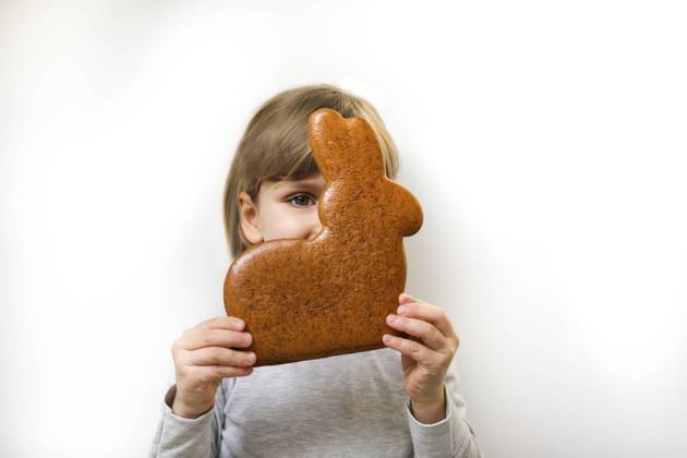 Girl with gingerbread Easter bunny covering face against white background model released, Symbolfoto, MOMF01009
