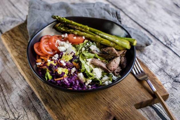 Bowl of salad with steak, asparagus, tomatoes, shredded red cabbage, lettuce and feta cheese, SBDF04609