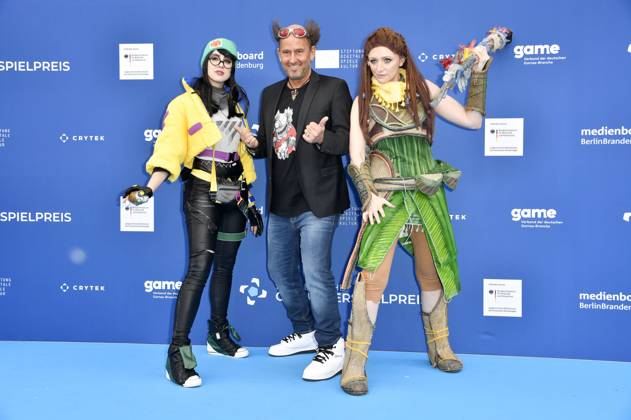 Tom Lehel mit den Cosplayern Killjoy und Aloy bei der Verleihung des Deutschen Computerspielpreises 2023 im Spindler & Klatt. Berlin, 11.05.2023