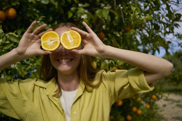 Woman covering eyes with orange slices at orchard model released, Symbolfoto property released, ANNF00237