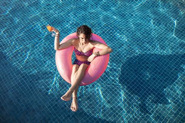 Woman holding drink floating in swimming pool at sunny day model released, Symbolfoto, IKF00258