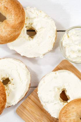 Bagel Brötchen Sandwich zum Frühstück belegt mit Frischkäse auf Holzbrett von oben Hochformat in Stuttgart, Deutschland Stuttgart, Deutschland - 18. März 2023: Bagel Brötchen Sandwich zum Frühstück belegt mit Frischkäse auf Holzbrett von oben Hochformat in Stuttgart, Deutschland. Copyright: xZoonar.com MarkusxMainkax 20135201