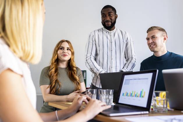 Smiling colleagues looking at businesswoman with laptop in office model released, Symbolfoto property released, WPEF06648