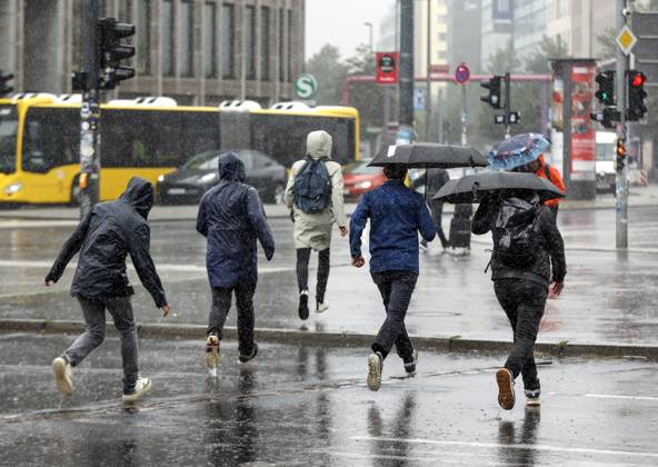 Regenwetter Berlin, 23.06.2023 - Menschen in Regenkleidung rennen bei starkem Regenfall ueber einen Fussgaengerueberweg. Starke Unwetter sind ueber Teile Deutschlands gezogen. Berlin Berlin Deutschland