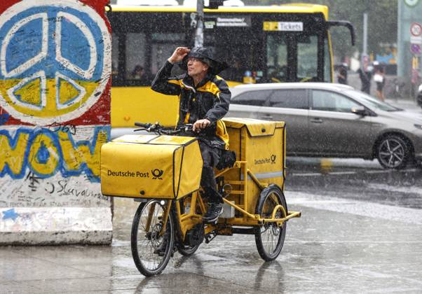 Regenwetter Berlin, 23.06.2023 - Ein DHL Briefzusteller faehrt mit seinem E-Bike bei starkem Regen ueber einen Gehweg. Starke Unwetter sind ueber Teile Deutschlands gezogen. Berlin Berlin Deutschland