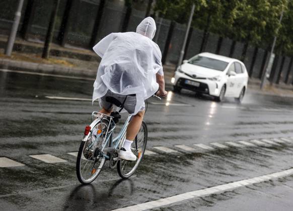 Regenwetter Berlin, 23.06.2023 - Ein Fahrradfharer schuetzt sich mit einem Regencape vor starkem Regenfall. Starke Unwetter sind ueber Teile Deutschlands gezogen. Berlin Berlin Deutschland