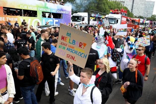 CHRISTOPHER STREET DAY 2023 - BERLIN PRIDE 2023 - CSD Berlin - Am 22. Juli 2023 zieht der CSD in Berlin unter dem bilingualen Motto BE THEIR VOICE AND OURS! ... FÜR MEHR EMPATHIE UND SOLIDARITÄT! zum 45. Mal durch die Hauptstadt. Die bunte CSD-Parade startet als Demonstration an der Leipziger Straße und führt auf einer 7,4 Kilometer langen Strecke über den Potsdamer Platz, vorbei am Nollendorfplatz, über die Siegessäule (Großer Stern) und der Straße des 17. Juni zum Endpunkt am Brandenburger Tor. Die Veranstalter rechnen im Tagesverlauf mit bis zu 500.000 Teilnehmerinnen und Teilnehmern. Demoteilnehmer trägt Protestschild: HOMOPHOBIE ist HEILBAR! - JEDER KANN LERNEN KEIN ARSCHLOCH ZU SEIN.