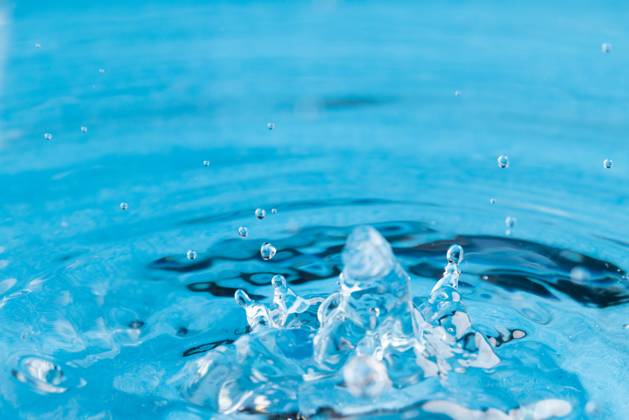 Close up of water drop falling into water with ripples and copy space on blue background. Water, liquid and colour concept. Copyright: xx 4132831