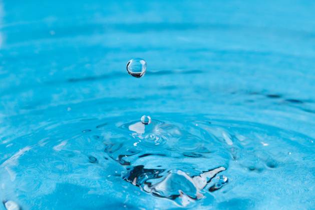 Close up of water drop falling into water with ripples and copy space on blue background. Water, liquid and colour concept. Copyright: xx 4132832