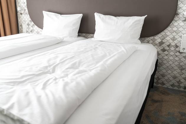 Bett in einem Hotelzimmer mit weißer Bettdecke und weißen Kissen