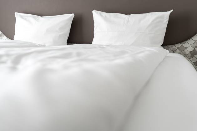 Bett in einem Hotelzimmer mit weißer Bettdecke und weißen Kissen
