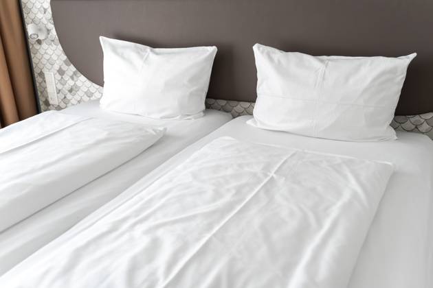Bett in einem Hotelzimmer mit weißer Bettdecke und weißen Kissen