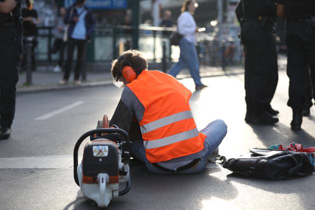 Berlin, Deutschland, 18.09.2023: Protest von Klimaaktivisten der Letzten Generation am Kottbusser Tor in Berlin-Kreuzberg. Einem Aktivisten wurden Ohrschutz, Augenschutz und Atemschutzmaske aufgesetzt, er wartet darauf, dass er mit einer Flex vom Straßenbelag abgelöst wird. Copyright: xdtsxNachrichtenagenturx dts_22245