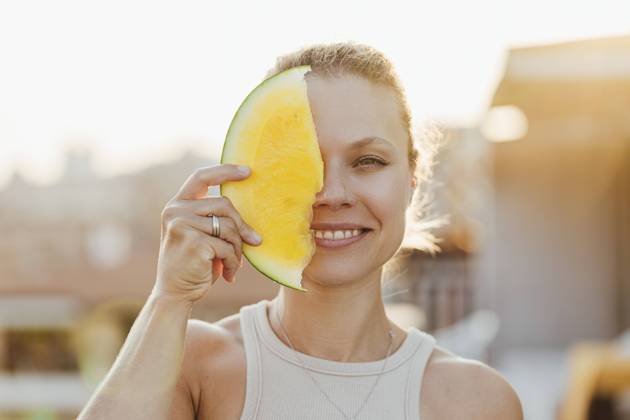 Smiling woman covering her face with yellow watermelon model released, Symbolfoto, SIF00810