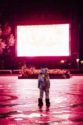 Spaceman on a square at night attracted by shining projection screen model released, Symbolfoto, VPIF00755