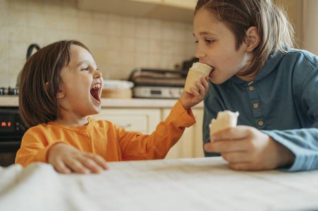 Happy boy feeding ice cream to brother at home model released, Symbolfoto property released, ANAF01484