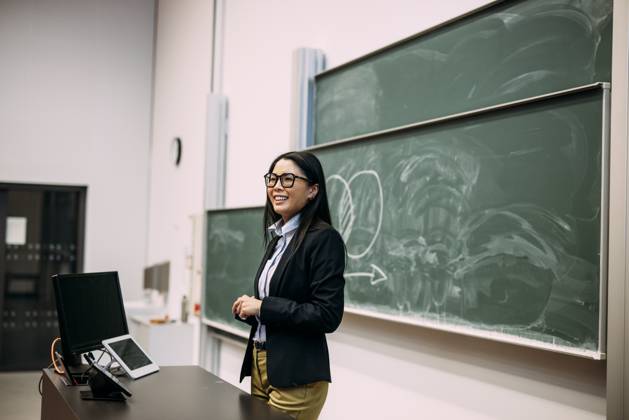 Smiling businesswoman standing in front of greenboard at auditorium model released, Symbolfoto property released, JOSEF21463