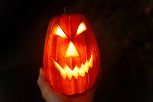 Hand holding scary Halloween pumpkin at night