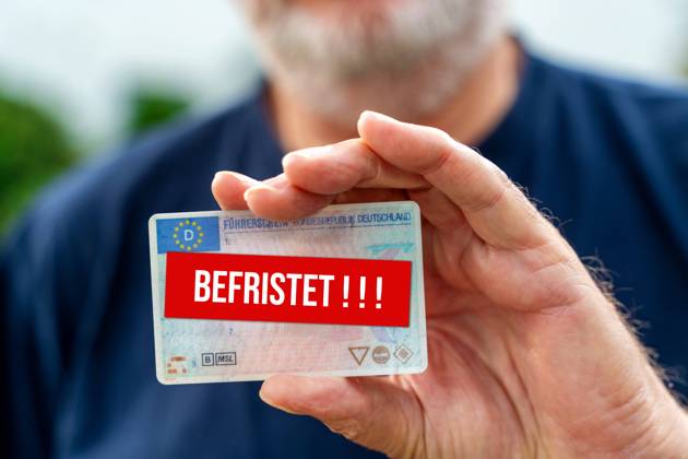 An old man with a beard holds a driver s license with the inscription Befristet. Driving safety and driver s license reform concept FOTOMONATE