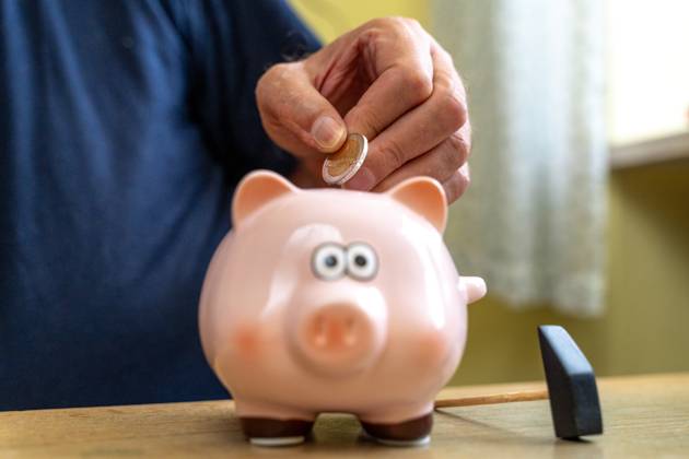 An old man throws euro coins into a piggy bank. Retirement provision concept