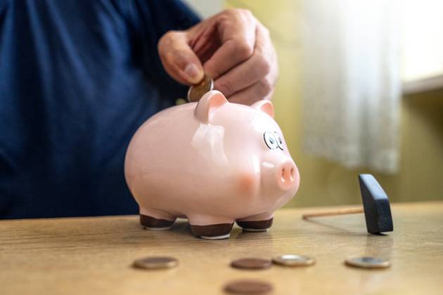 An old man throws euro coins into a piggy bank. Retirement provision concept