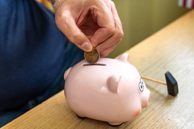 An old man throws euro coins into a piggy bank. Retirement provision concept