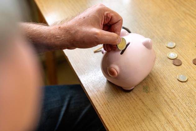 An old man throws euro coins into a piggy bank. Retirement provision concept