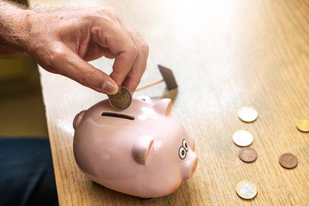 An old man throws euro coins into a piggy bank. Retirement provision concept