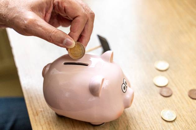 An old man throws euro coins into a piggy bank. Retirement provision concept
