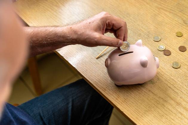 An old man throws euro coins into a piggy bank. Retirement provision concept