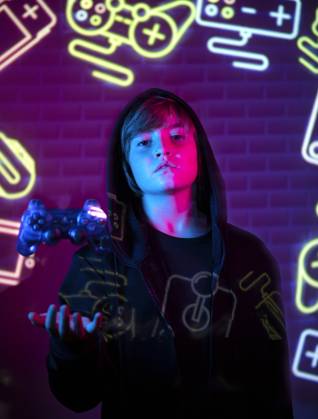 IMAGO Creative, Lifestyle, Gaming A young teen stands holding a game controller, bathed in the vibrant glow of neon lights with gaming symbols in the background. Model Released SergioVictorVega_ID17439_529355_007 Copyright: xSergioxVictorxVegax RECORD DATE NOT STATED