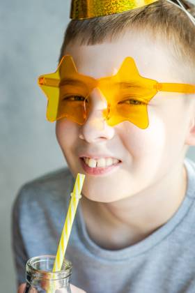 IMAGO Creative, Gesellschaft, Fasching A young boy with a playful smile wearing star-shaped sunglasses and drinking from a straw. Model Released AnnaBogush_ID18228_545531_001 Copyright: xAnnaxBogushx