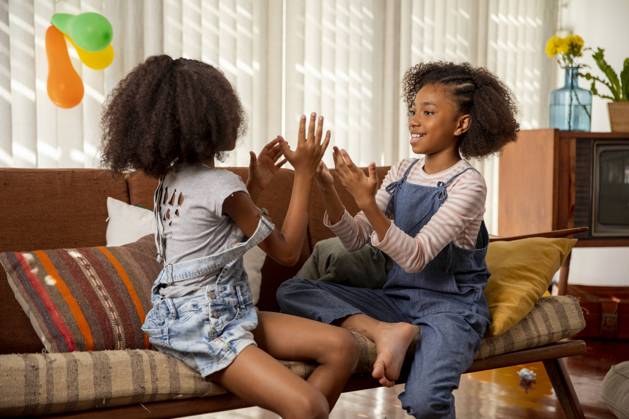 Happy girls playing clapping game on sofa at home model released, Symbolfoto property released, IKF01445
