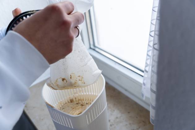 Mann wechselt das Granulat von einem Luftentfeuchter in einer Wohnung