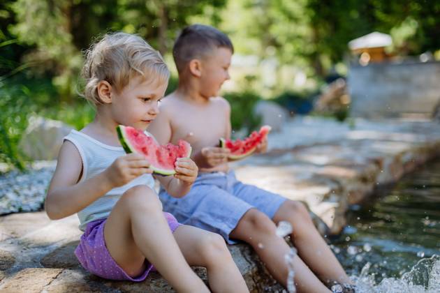 Little chidren sitting near lake and eating watermelon on hot sunny day during summer vacation. Little chidren sitting near a lake and eating watermelon on hot sunny day during summer vacation. model released Copyright: xx HHH SOLO TZ KYSUCE DOVOLENKA 2022 HHH 461