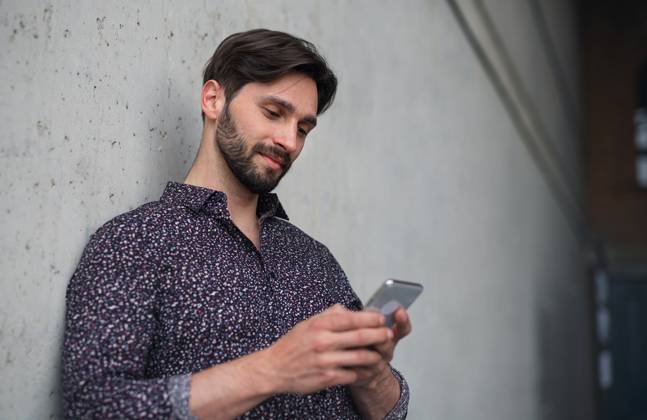 Portrait of young businessman standing indoors, using smarpthone. A portrait of young businessman standing indoors, using smarpthone. model released Copyright: xx Grand_Elektraren_Business_Portraits_2021_091