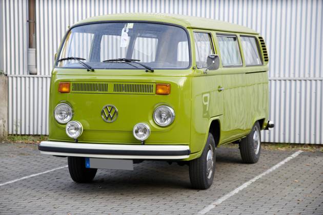 Oldtimer VW Bulli T2 Ein sehr gepflegter Grashuepfer gruener VW Bulli T2 steht auf einem eingezeichneten Parkplatz vor einer weissen Wellblechwand. Essen