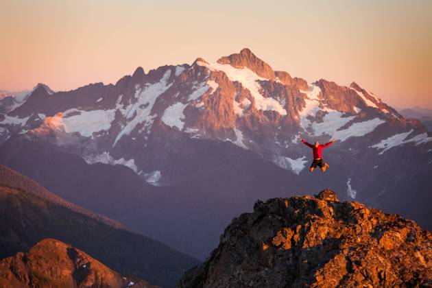 A hiker jumps off rocky cliff in North Cascades National Park. Glacier, Washington, United States CR_JDIP240227-1346428-01 ,model released, Symbolfoto