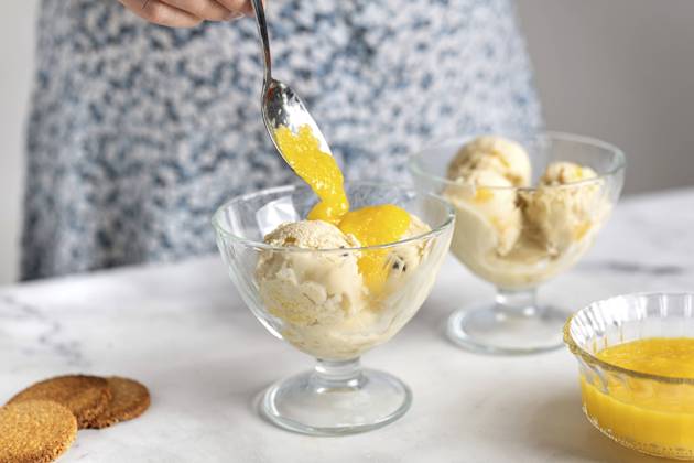Woman putting fruit sauce on ice cream in bowl model released, Symbolfoto, TILF00070