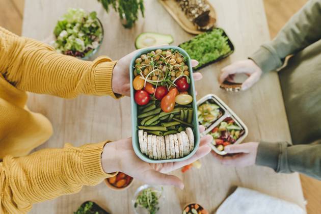 IMAGO Creative, Food, Trend, Meal Prep Hands of woman holding vegetarian food lunch box near man at table model released, Symbolfoto property released, YTF01686