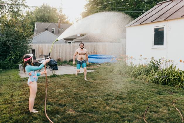 Young girl holds garden hose while dad runs through water Sioux Falls, South Dakota, United States CR_ASWE240317-1369123-01 ,model released, Symbolfoto ,property released