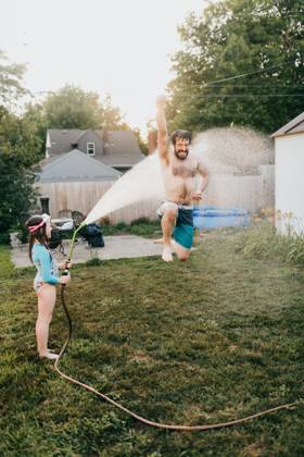 Young girl holds garden hose while dad runs through water Sioux Falls, South Dakota, United States CR_ASWE240317-1369125-01 ,model released, Symbolfoto ,property released