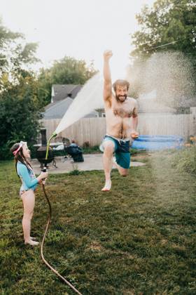 Young girl holds garden hose while dad runs through water Sioux Falls, South Dakota, United States CR_ASWE240317-1369126-01 ,model released, Symbolfoto ,property released