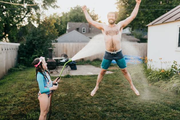 Young girl holds garden hose while dad runs through water Sioux Falls, South Dakota, United States CR_ASWE240317-1369151-01 ,model released, Symbolfoto ,property released