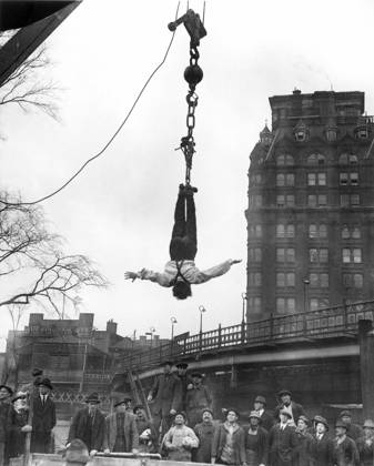 HARRY HOUDINI (1874-1926). American magician. Houdini at finish of stunt of releasing himself from a straitjacket while suspended in midair; photographed in 1916.  Copyright: xGRANGERx xGRANGERx 0016939
