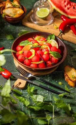 Spicy salad of fresh watermelon balls with basil, lime, rosemary and fennel, topping with olive oil Spicy salad of fresh watermelon balls with basil, lime, rosemary and fennel, topping with olive oil on dark green table surface with sunny light Copyright: xZoonar.com VictoriaxKondysenkox(ArtSvitlyna)x 20788119