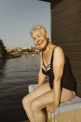 Portrait of happy senior woman wearing swimsuit while sitting near lake on houseboat Germany, Berlin, model released, property released Copyright: xMaskotx , MA108722 MA108722