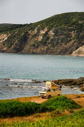 Old retro yellow camper van near the sea on a wild landscape Magazzini, Sardegna, Italy CR_UGOUSD240415-1391158-01