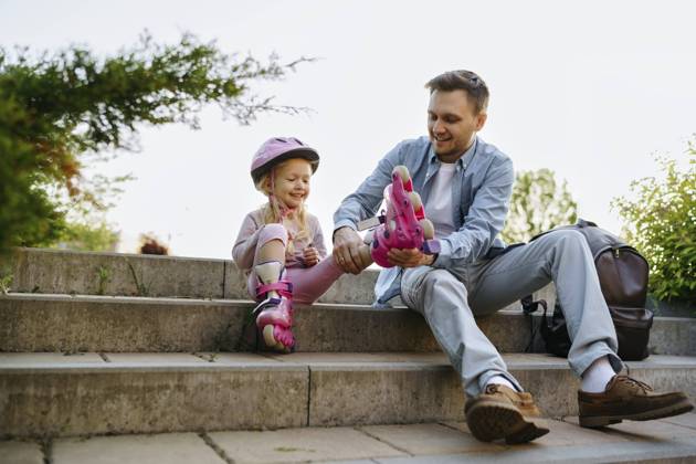 Smiling man helping daughter to wear roller skates sitting on steps model released, Symbolfoto, NSTF00054
