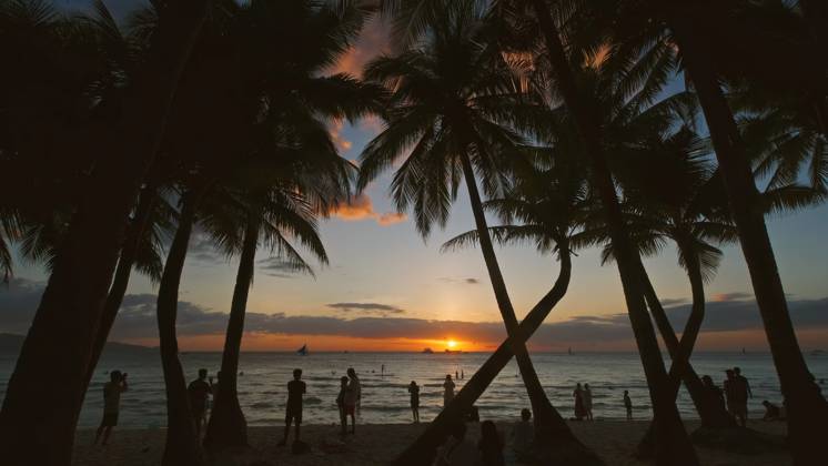 Sunset on beach with people and palms Silhouetted people and palms near sea. Sunset at tropical White beach, Boracay island, Philippines Copyright: xZoonar.com MikhailxKokhanchikovx 21445800